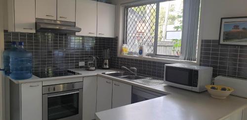 a kitchen with a sink and a microwave at Mick's Shared Townhouse in Kallangur