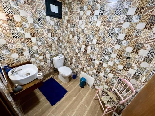 a bathroom with a toilet and a tiled wall at Victoria Ocean View Room in Ponta do Pargo