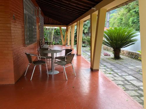 patio ze stołem i krzesłami na ganku w obiekcie Sítio dos Guedes w mieście Guapimirim