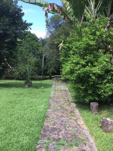 a stone path in a field of grass with trees at Sítio dos Guedes in Guapimirim