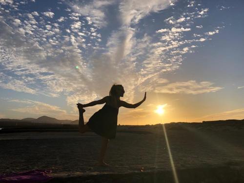 a woman dancing in a field with the sun in the background at LANZATE! in Tinajo