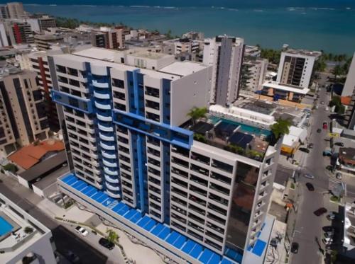 a large white building with blue accents in a city at Edf Time Ponta Verde, Studio 523 in Maceió