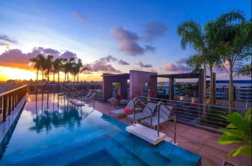 una piscina de hotel con puesta de sol en el fondo en Edf Time Ponta Verde, Studio 523, en Maceió