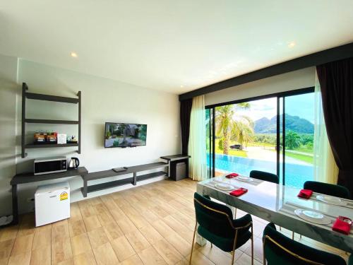 a living room with a table and chairs and a large window at Belong Jin The Dam Hotel And Resort in Ban Pha Saeng Lang