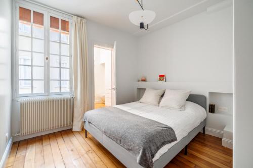 a white bedroom with a bed and a window at Luxury Living à Montorgueil in Paris