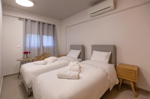 two beds in a room with white sheets and towels at La Villa del Mare - Nafpaktos Beach in Nafpaktos