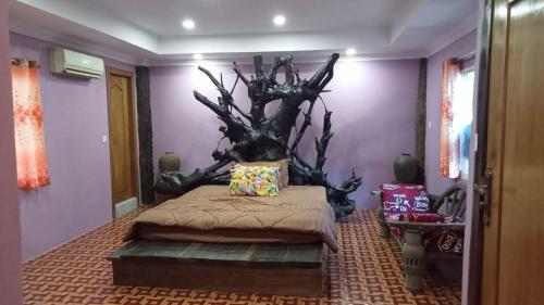 a bedroom with a bed with a tree branch on the wall at Kakrona Pouk Homestay in Siem Reap