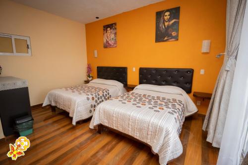 two beds in a room with yellow walls at Hotel Jatziri in San Juan Teotihuacán