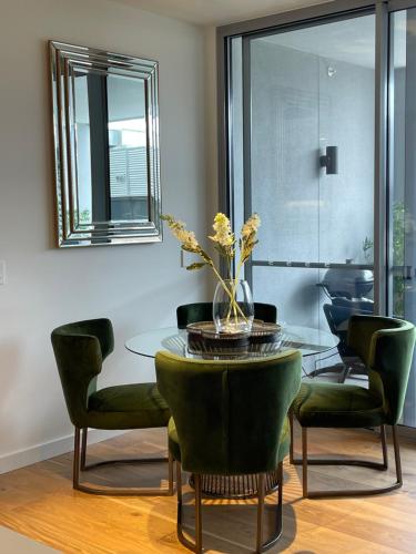 a dining room with a glass table and green chairs at Little Lane Apartments Comfortable, Chic New Apartment in Heart Of Fremantle Features Large balcony & Free car bay in Fremantle
