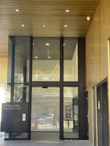 a building with a glass door with a sign in it at Little Lane Apartments Comfortable, Chic New Apartment in Heart Of Fremantle Features Large balcony & Free car bay in Fremantle