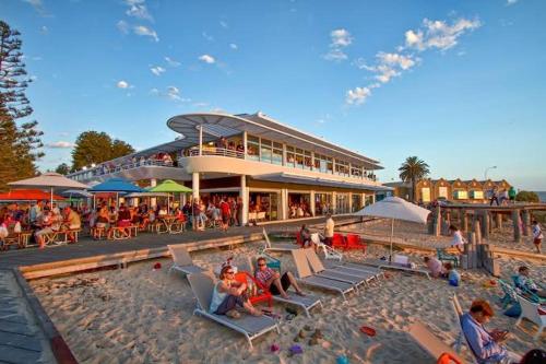 a group of people sitting on the beach near a hotel at Little Lane Apartments Comfortable, Chic New Apartment in Heart Of Fremantle Features Large balcony & Free car bay in Fremantle