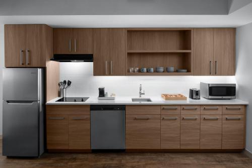 a kitchen with wooden cabinets and a stainless steel refrigerator at Element San Antonio Riverwalk in San Antonio