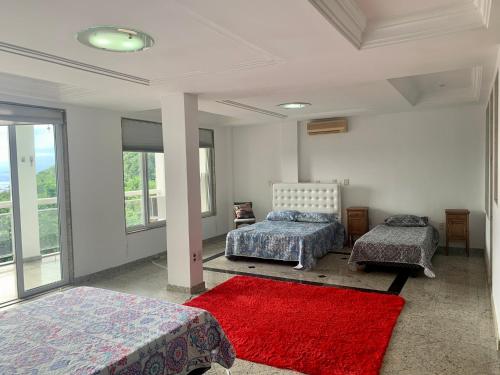 a bedroom with two beds and a red rug at Casa Aurora Luz do Amanhecer in Rio de Janeiro