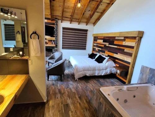 1 dormitorio con 1 cama y bañera en una habitación en Cabañas Santorito, en Mazamitla