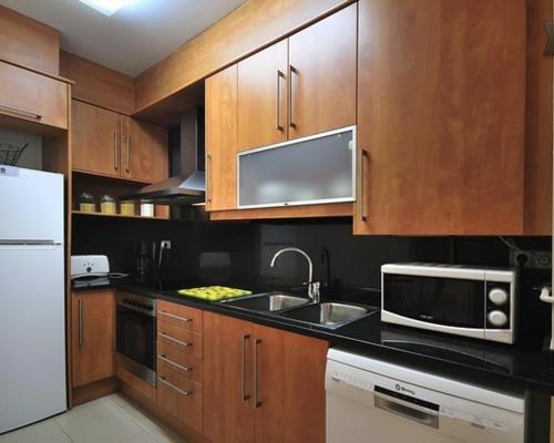 a kitchen with wooden cabinets and a sink and a microwave at Vivalidays Abril in Blanes