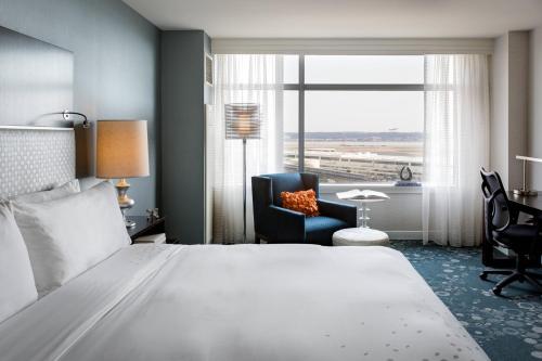 um quarto de hotel com uma cama e uma cadeira e uma janela em Renaissance Arlington Capital View Hotel em Arlington