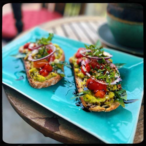 two pieces of toast with vegetables on a blue plate at The Happy Bird B&B in Hoi An
