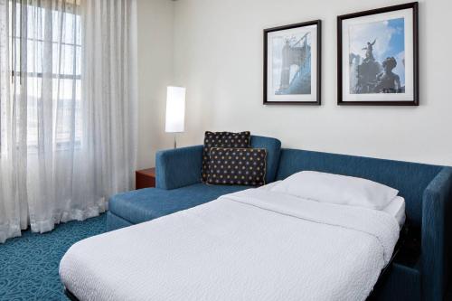 a hotel room with a bed and a blue couch at Residence Inn by Marriott Cincinnati Downtown/The Phelps in Cincinnati