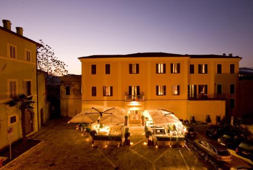 a building with tables and umbrellas in a courtyard at Hotel Clitunno in Spoleto