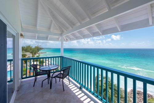a balcony with a table and chairs and the ocean at Rostrevor Hotel in Christ Church