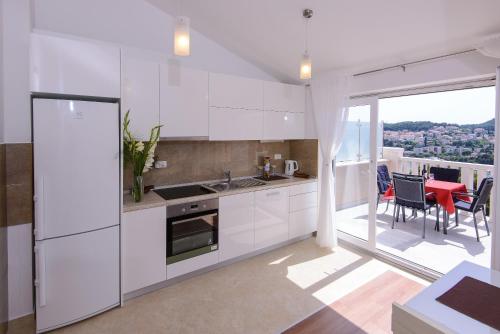 a kitchen with white cabinets and a table with chairs at Apartment Violeta 2 with parking in Dubrovnik