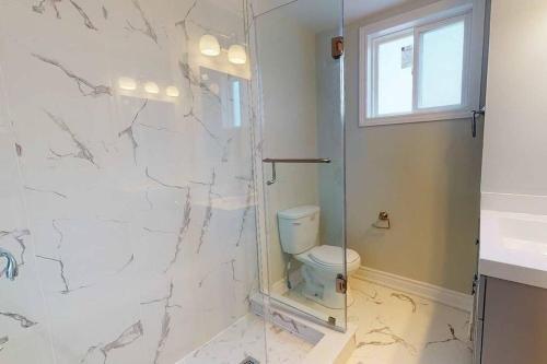 a bathroom with a toilet and a glass shower at 3-Bedroom House in Little Italy Downtown-Free Parking in Toronto
