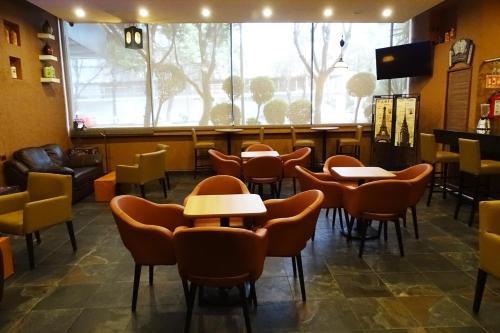 a restaurant with tables and chairs and a large window at Hotel Oslo in Mexico City