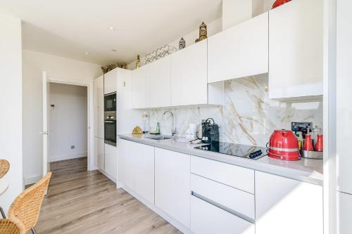 a white kitchen with white cabinets and wood floors at Penthouse With Views Of Alexandra Palace in London