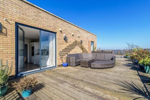 a patio with a couch on a wooden deck at Penthouse With Views Of Alexandra Palace in London