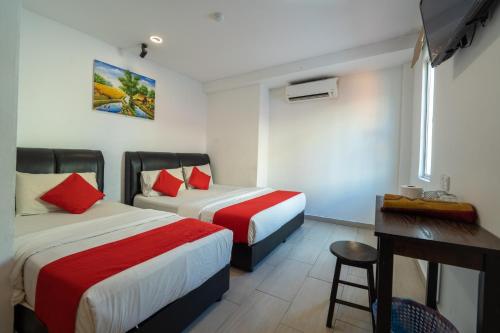 哥打巴魯的住宿－MRJ Hotel Wakaf Che Yeh 1，酒店客房设有两张床、一张桌子和一张书桌。