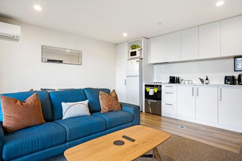 een woonkamer met een blauwe bank en een keuken bij 1 Bedroom City Base with Free Car Park in Christchurch