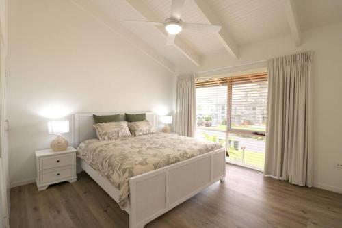 ein weißes Schlafzimmer mit einem Bett und einem Fenster in der Unterkunft Beach Haven in Merimbula
