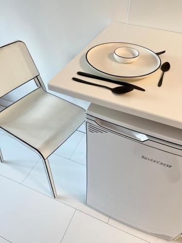 a white table and chair with a plate on it at 2D Apartment in Szekszárd