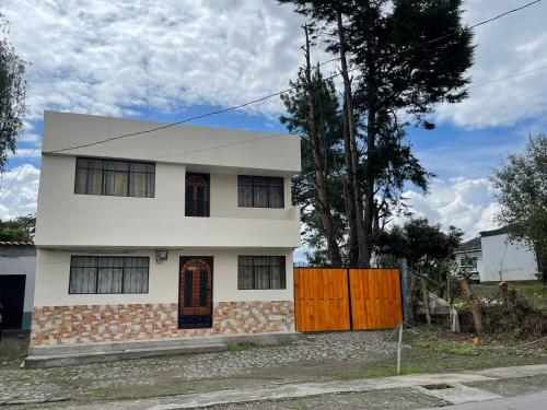 ein weißes Haus mit einem Zaun davor in der Unterkunft Casa Museo - Naturaleza y Tradición in Otavalo