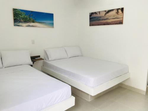 Duas camas num quarto com paredes brancas em Hostería Altamar Tolú em Tolú