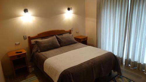 um quarto com uma cama e duas luzes na parede em Parcela Parulus em Valdivia