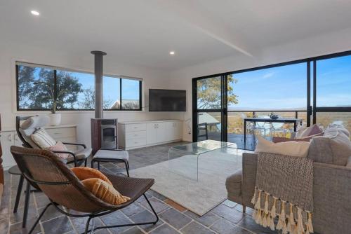 a living room with a couch and chairs and windows at Aqua La Vista - 4 Bedroom Pet Friendly House in Merimbula