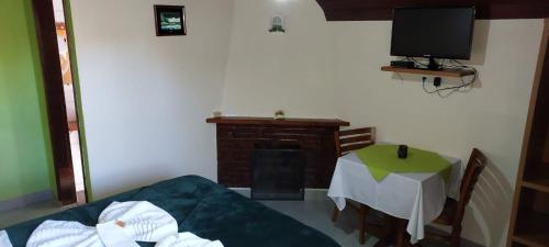 uma sala de estar com uma mesa e uma televisão em Casa Moreira´s Chalés em Monte Verde