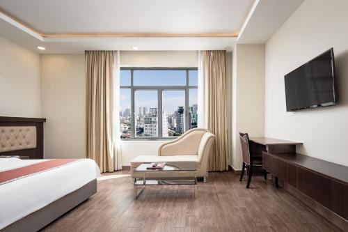 プノンペンにあるHM Grand Central Hotelのベッド、デスク、テレビが備わるホテルルームです。