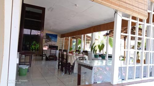 a dining room with tables and chairs and windows at EL Homestay Bunaken in Bunaken