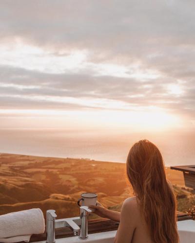 a woman sitting in a bath tub looking out at the ocean at Matai Peak Lodge in Hundalee