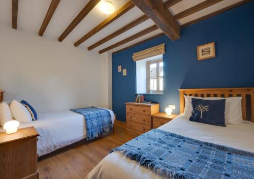 ein Schlafzimmer mit 2 Betten und einer blauen Wand in der Unterkunft Stabal y Gelli in Trawsfynydd