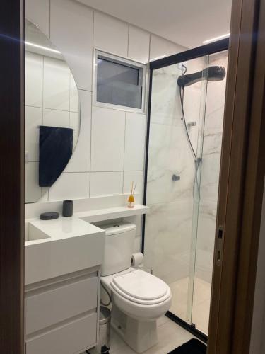 a white bathroom with a toilet and a shower at Apartamento Completo Jatiúca in Maceió
