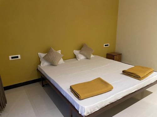 Una cama con sábanas blancas y almohadas marrones. en Scarlet Resort Alibag en Alibaug