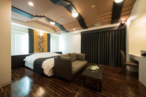 Habitación de hotel con cama, sofá y mesa en Hotel Rea Tiare - Adult Only-, en Himeji