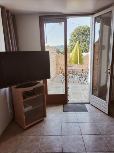 a living room with a flat screen tv and a patio at A deux pas de Cabourg ,avec une belle vue sur la campagne normande.A grangues in Grangues
