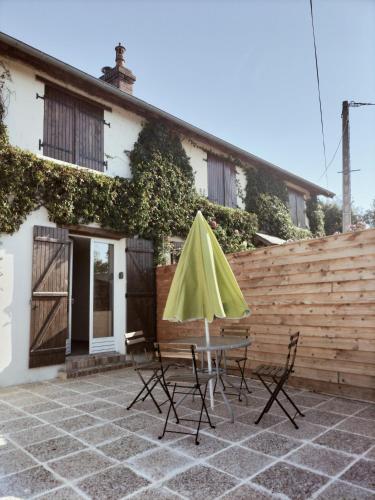 a table and chairs with a yellow umbrella on a patio at A deux pas de Cabourg ,avec une belle vue sur la campagne normande.A grangues in Grangues