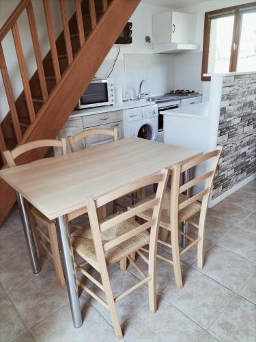a kitchen with a wooden table and chairs at A deux pas de Cabourg ,avec une belle vue sur la campagne normande.A grangues in Grangues