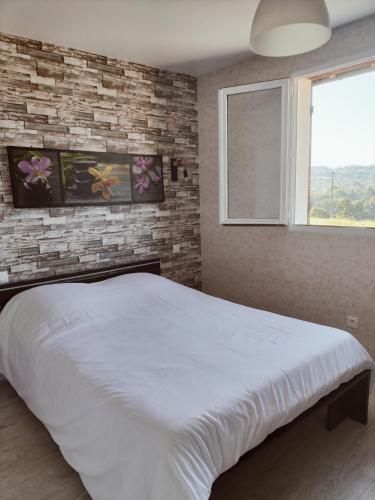 a bedroom with a white bed and a brick wall at A deux pas de Cabourg ,avec une belle vue sur la campagne normande.A grangues in Grangues