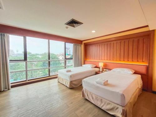 a hotel room with two beds and a large window at Ebina House - SHA Extra Plus in Bangkok